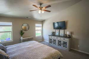 Carpeted bedroom with lofted ceiling, a textured ceiling, and ceiling fan