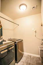 Clothes washing area with washer and clothes dryer and a textured ceiling