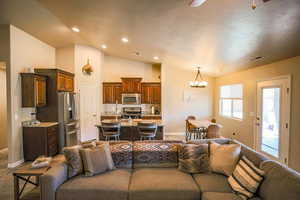 Living room featuring lofted ceiling, a textured ceiling, and an inviting chandelier