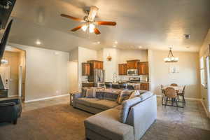 Tiled living room featuring ceiling fan with notable chandelier and vaulted ceiling