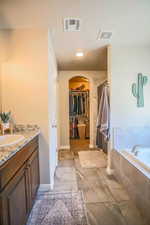 Bathroom featuring vanity and tiled bath