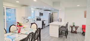 Kitchen featuring sink, a breakfast bar area, white cabinetry, appliances with stainless steel finishes, and light hardwood / wood-style floors