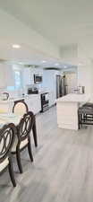 Kitchen featuring sink, white cabinetry, appliances with stainless steel finishes, kitchen peninsula, and light hardwood / wood-style floors