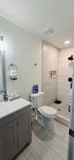 Bathroom with vanity, a textured ceiling, toilet, and a tile shower