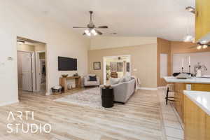 Living room featuring sink, light hardwood / wood-style flooring, high vaulted ceiling, and ceiling fan