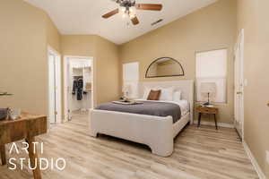 Bedroom with a walk in closet, lofted ceiling, ceiling fan, and light hardwood / wood-style flooring