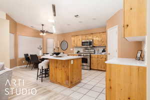 Kitchen featuring appliances with stainless steel finishes, a kitchen breakfast bar, decorative backsplash, a kitchen island with sink, and light tile patterned floors