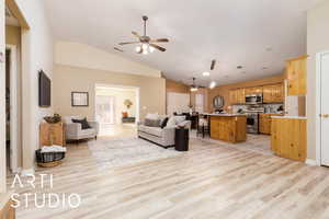 Living room featuring vaulted ceiling, ceiling fan, and light wood-type flooring