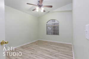 Spare room featuring ceiling fan, vaulted ceiling, and light wood-type flooring