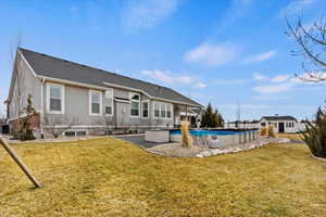 Back of house with a lawn and a covered pool