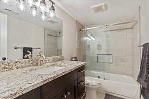 Full bathroom featuring toilet, vanity, and shower / bath combination with glass door