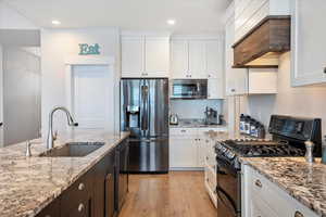 Kitchen with sink, white cabinets, and black appliances