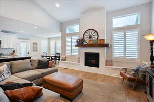 Living room featuring high vaulted ceiling, a fireplace, and light hardwood / wood-style flooring