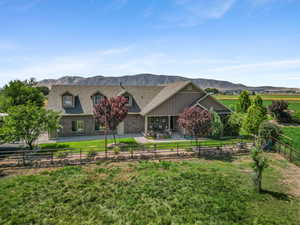 Back of house with a mountain view, a fenced backyard, a patio area, brick siding, and roof with shingles