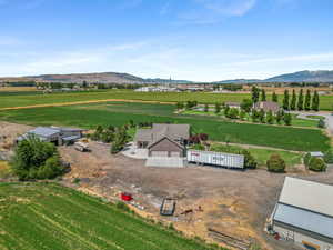 Aerial view of sparsely populated area featuring a mountain backdrop and large plots for crops
