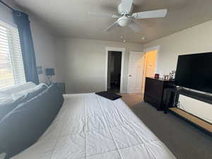 Bedroom with ceiling fan, carpet, and a textured ceiling