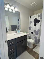 Bathroom with vanity, a textured ceiling, and toilet and shower/tub