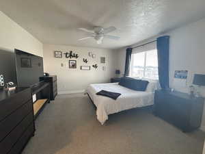 Bedroom with ceiling fan, carpet floors, and a textured ceiling