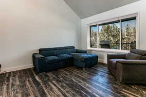 Living room with lofted ceiling, dark wood-type flooring, and a textured ceiling