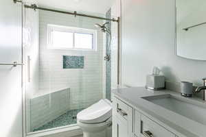 Bathroom with vanity, an enclosed shower, and toilet