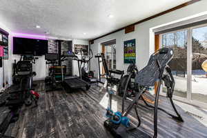 Gym with a wood stove, hardwood / wood-style floors, and a textured ceiling