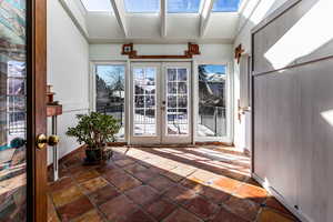 Interior space featuring plenty of natural light, vaulted ceiling with skylight, and french doors