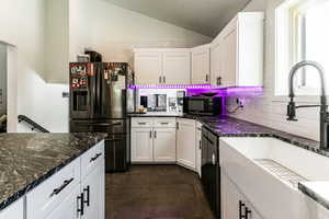 Kitchen featuring fridge with ice dispenser, sink, white cabinetry, and a wealth of natural light