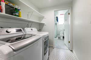 Washroom with light tile patterned flooring and washing machine and clothes dryer