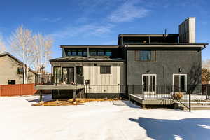 Snow covered house featuring a wooden deck