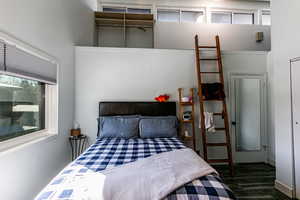 Bedroom with a towering ceiling and dark hardwood / wood-style flooring