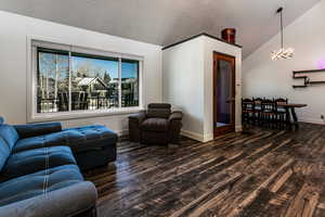 Living room featuring dark wood-type flooring, a textured ceiling, and a notable chandelier