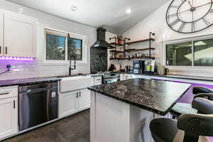 Kitchen with white cabinets, stainless steel appliances, sink, and wall chimney range hood