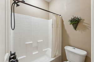 Bathroom with shower / bathtub combination with curtain and toilet