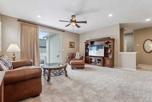 Living room featuring ceiling fan and light carpet