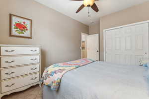 Carpeted bedroom featuring ceiling fan and a closet