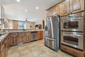 Kitchen with light stone counters, appliances with stainless steel finishes, kitchen peninsula, and sink