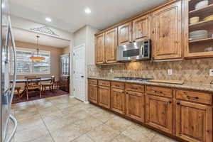 Kitchen with light stone counters, decorative backsplash, stainless steel appliances, and light tile patterned flooring