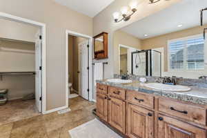 Bathroom with walk in shower, vanity, toilet, and tile patterned flooring