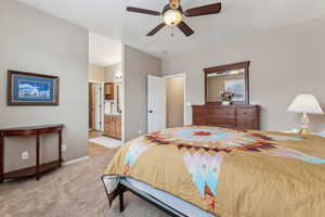 Bedroom with ceiling fan, light colored carpet, and ensuite bath