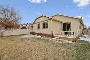 Back of house with a wooden deck and a yard