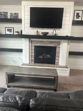 Room details featuring a fireplace, carpet floors, and wood walls