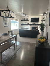 Living room with dark hardwood / wood-style floors, track lighting, a textured ceiling, and a fireplace