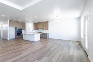 Kitchen with built in microwave, decorative light fixtures, an island with sink, oven, and backsplash