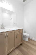 Bathroom with hardwood / wood-style flooring, walk in shower, vanity, and toilet