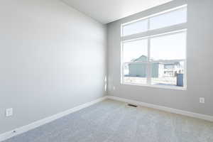 Carpeted spare room featuring a healthy amount of sunlight