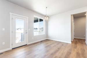 Unfurnished dining area with a notable chandelier and light hardwood / wood-style floors