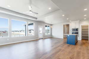 Kitchen featuring hanging light fixtures, light wood-type flooring, a center island with sink, stainless steel microwave, and white cabinets