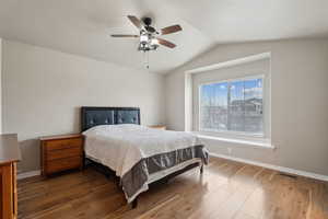 Bedroom with dark wood-type flooring, ceiling fan, and vaulted ceiling