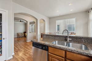 Kitchen with dishwasher, stone countertops, sink, and light hardwood / wood-style flooring