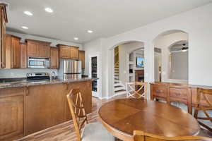 Kitchen featuring sink, light hardwood / wood-style flooring, built in features, dark stone countertops, and stainless steel appliances